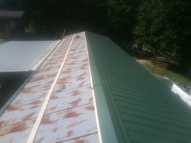 Old rusted panels beside newly installed green metal roofing — Wind Damage Roof Repair by Roofing Brothers in Fingal