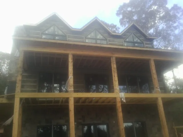Dormers and porch framing on a large log home under construction — Roof Coating work by our crew in Fingal