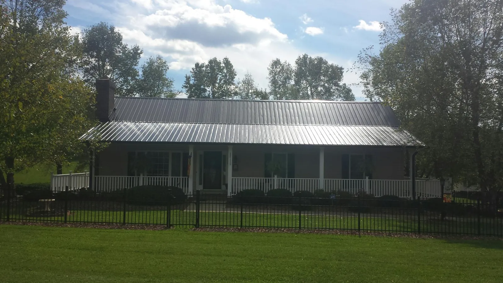 Gray metal roof on a brick ranch with a full width front porch — Gutter Guard Installation work by our crew in Fingal