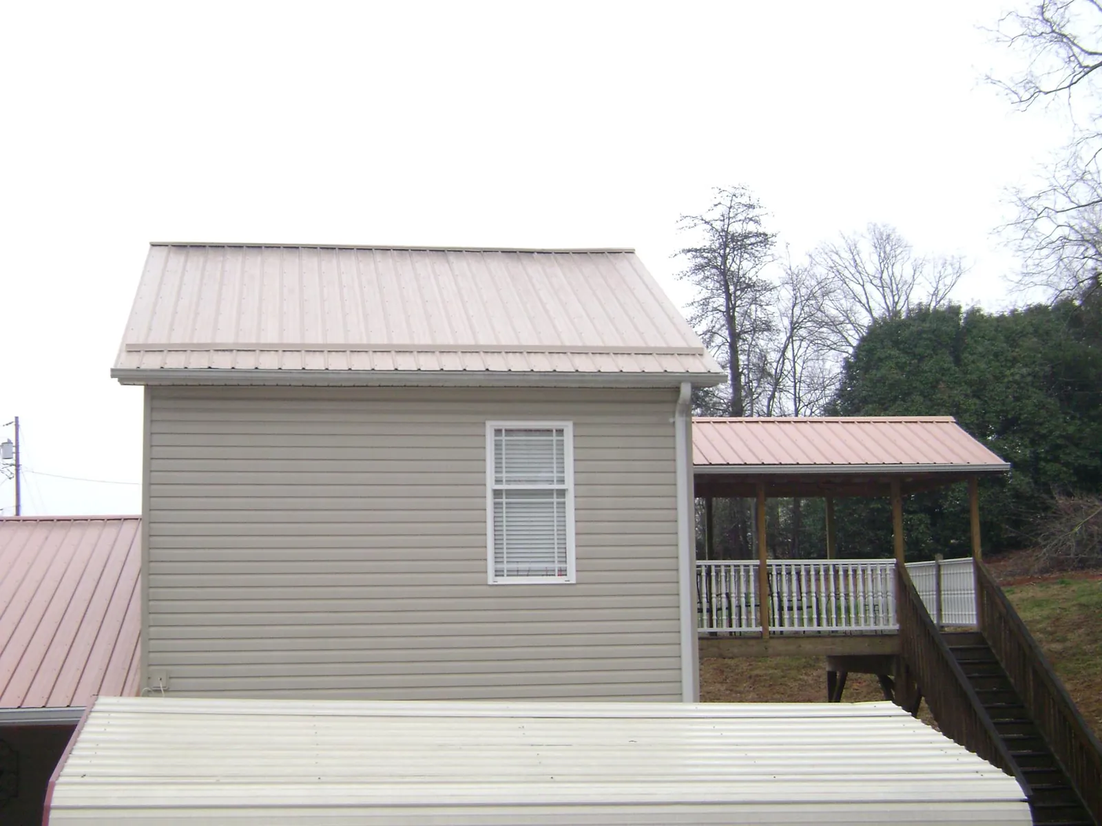Tan metal roofs on a two story addition and attached porch, from a Roof Replacement job in Fingal