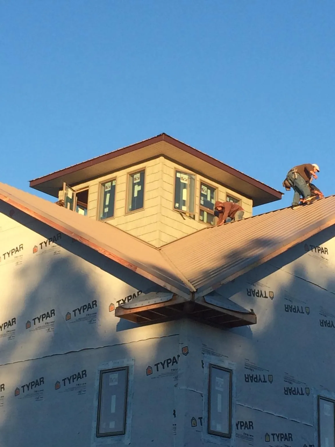 Roofers working around a rooftop cupola on a new metal roof at sunset — Roof Waterproofing in Fingal by Roofing Brothers